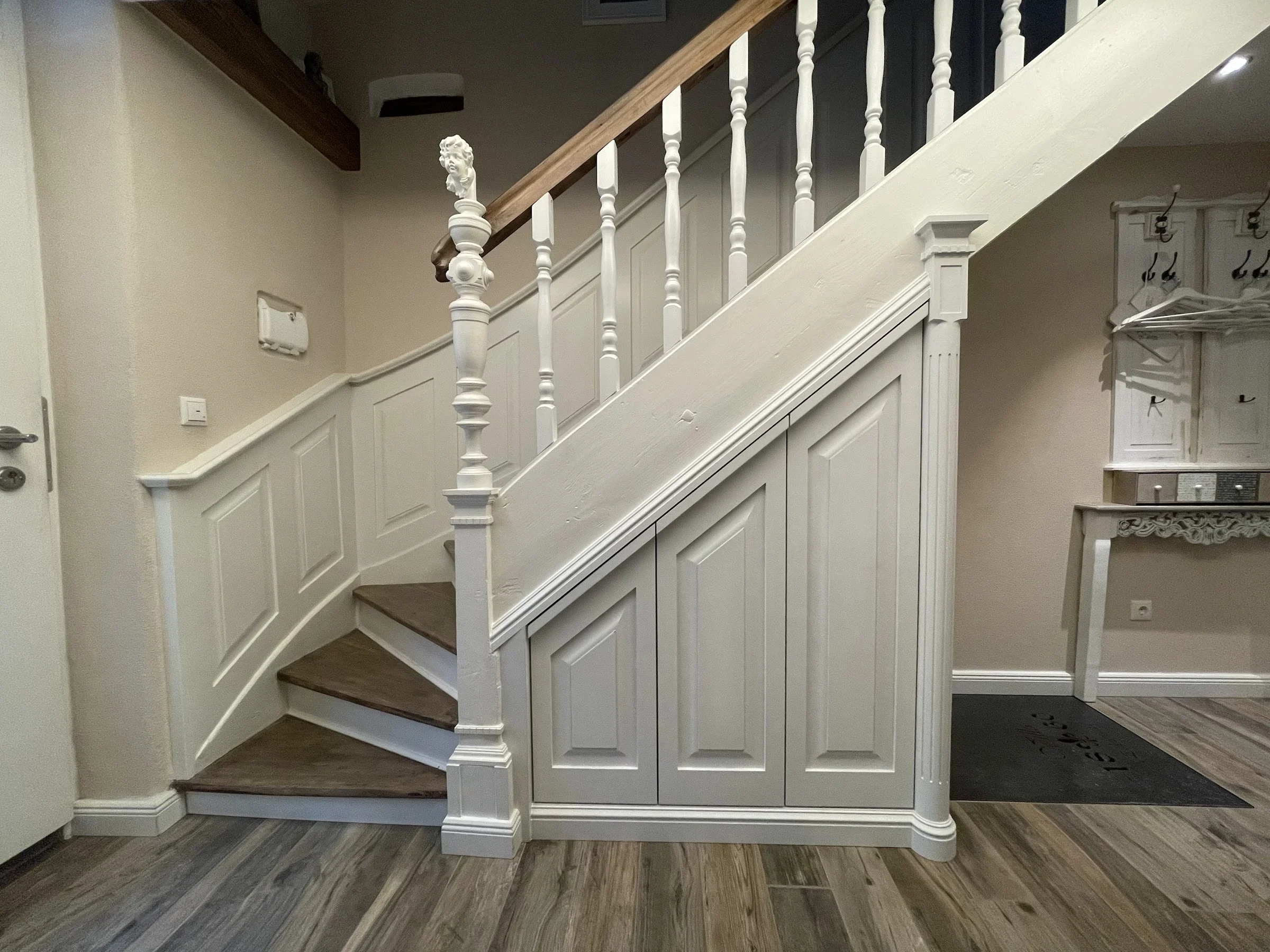 Under-stair cupboard and wall panelling along a historic staircase.