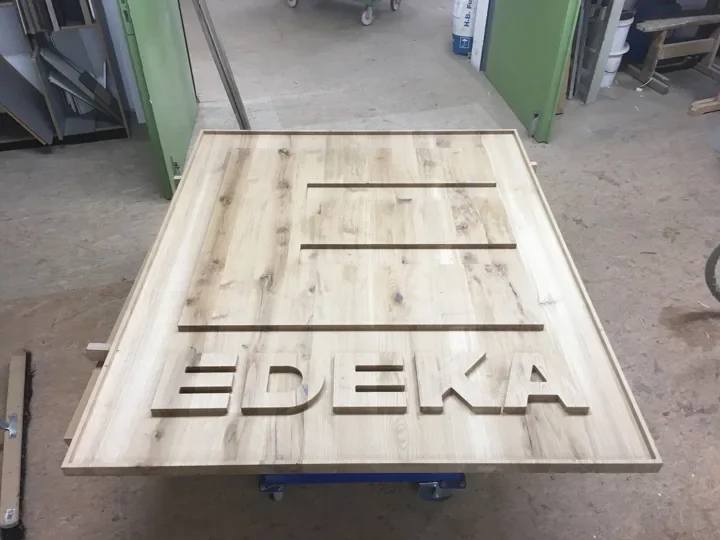 Gefräster Schriftzug und Logo in einer Holzplatte