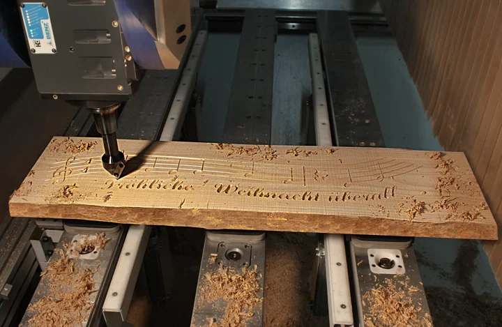 CNC engraving of musical notes and a German Christmas greeting in a wooden board