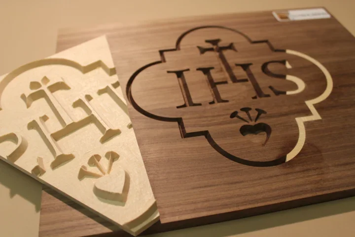 Solid-wood inlay: machined recess and matching light-wood insert with an IHS motif